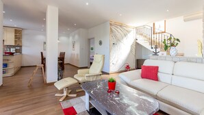 Uma sala de estar moderna com um sofá, uma mesa de centro e uma área de jantar com cadeiras e uma mesa.