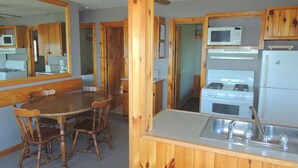 Una cocina compacta con gabinetes de madera, un microondas, una estufa y un lavaplatos.