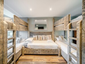 Une chambre avec des lits superposés, un lit au milieu et un miroir au mur.
