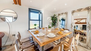 A dining area with a wooden table set for four, surrounded by chairs, a large mirror, and a window with a view. - 5 bedroom accommodation in Bowness-on-Solway (Bowness-on-Solway)