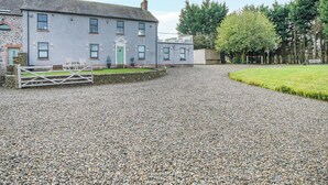 A two-story building with a gravel driveway, a wooden gate, and a grassy lawn. - 5 bedroom accommodation in Bowness-on-Solway (Bowness-on-Solway)