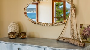 A mirror with a seashell frame, a small decorative sail, and a vase with seashells on a dresser. - Avra Apartments (Apokoronas)