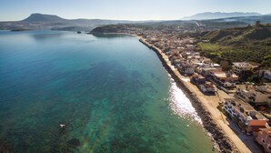 A coastal town with clear waters, a beach, and buildings along the shore. - Avra Apartments (Apokoronas)