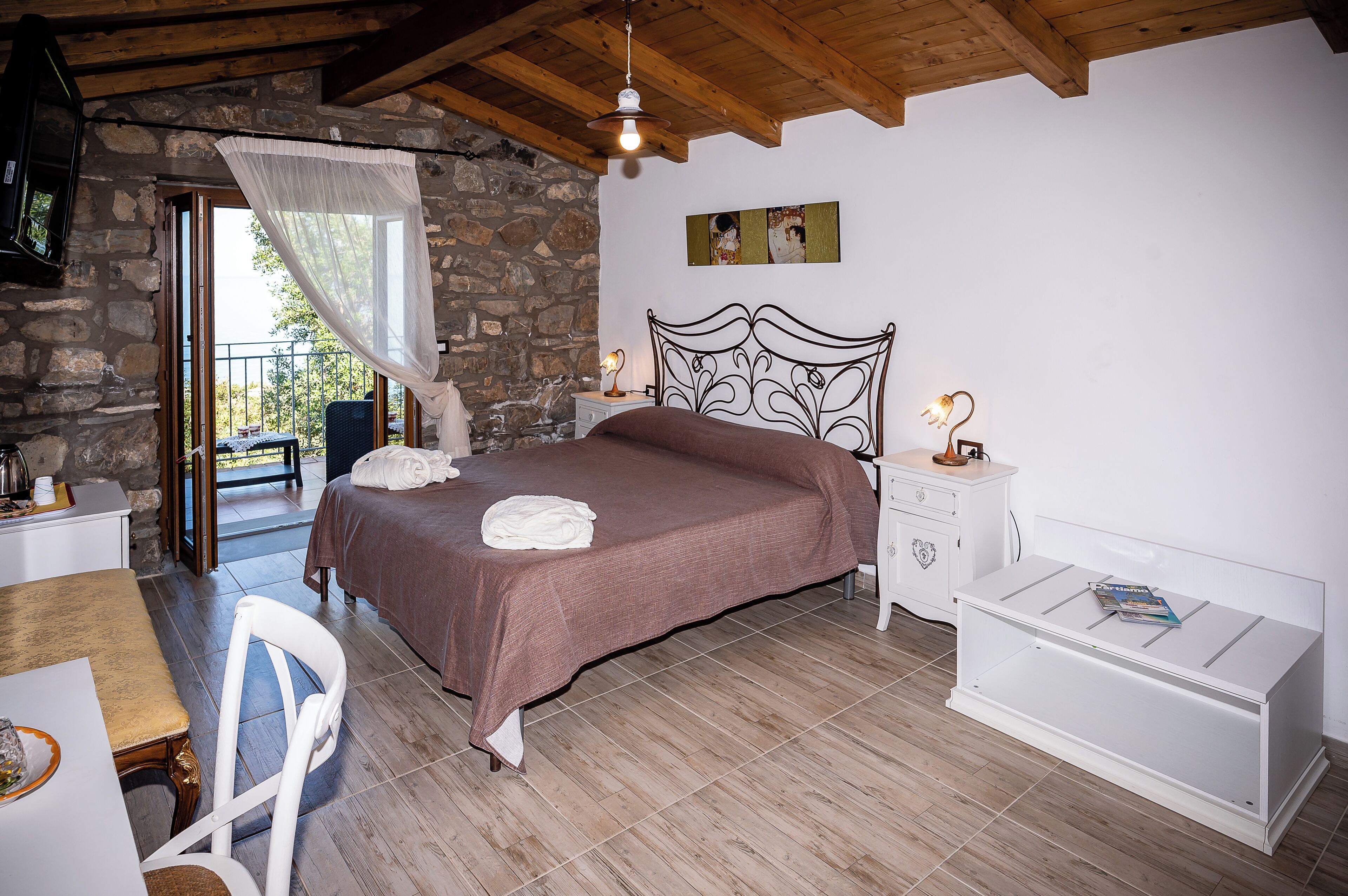 Une chambre à coucher comprenant un lit, une table de chevet, une chaise, une petite table et une fenêtre donnant sur un paysage agréable.