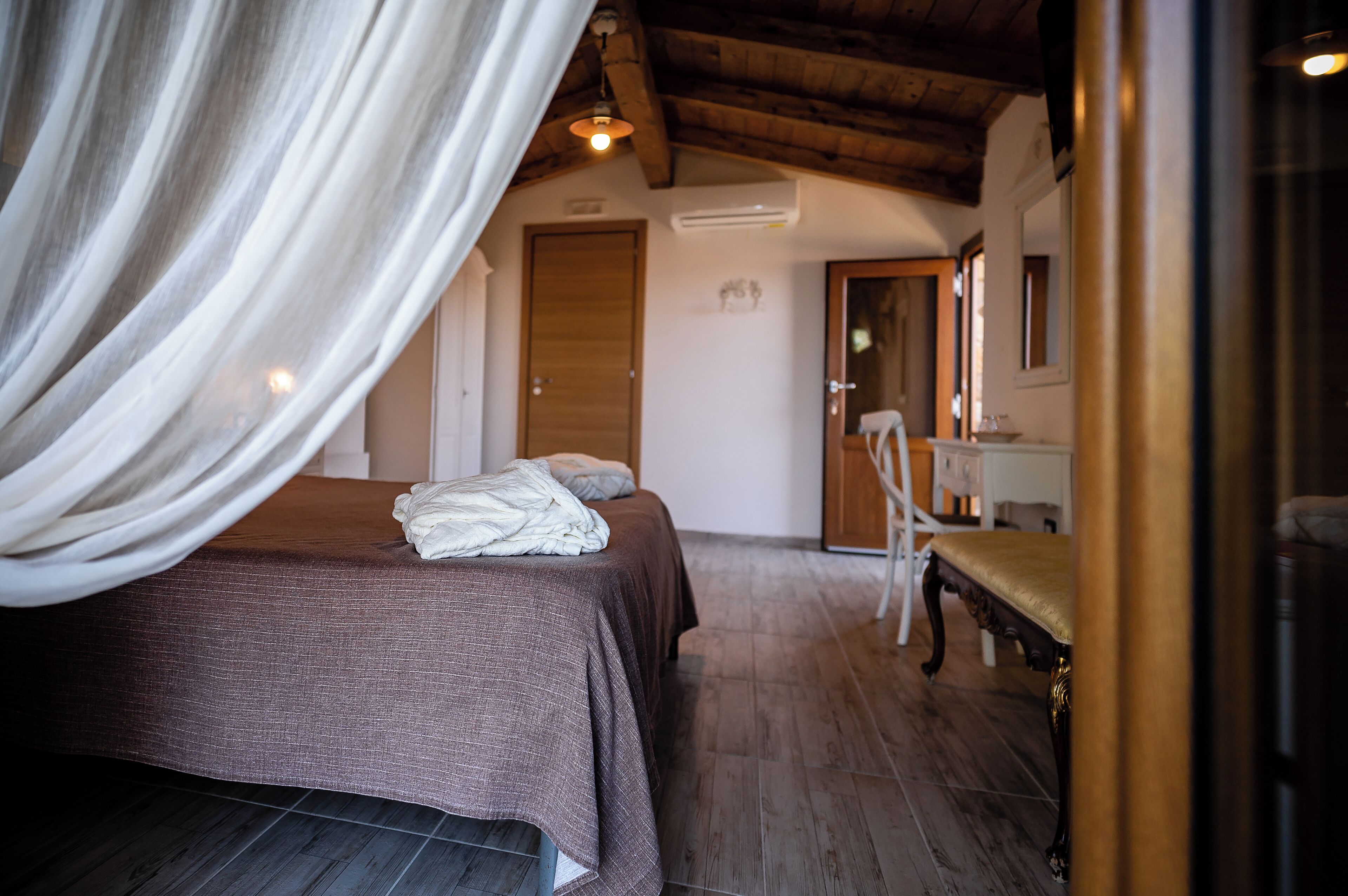 Un dormitorio con cama, un banco y suelo de madera.