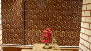 Un coin repas avec un mur orné d’un motif hexagonal, une table en bois avec des bancs, et un appareil de climatisation installé au-dessus.