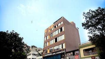 Charyana Hotel & Dormitory features a multi-story building with multiple rooms and a mix of light and dark panels on its facade.