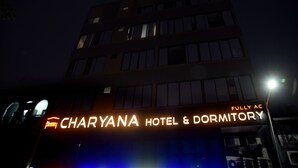 Une enseigne d’hôtel indiquant « CHARYANA HOTEL & DORMITORY » et « ENTIÈREMENT CLIMATISÉ », ce qui signifie que l’établissement est entièrement équipé de la climatisation.