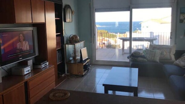 A living room with a television, a sofa, a coffee table, and a view of the sea through a sliding glass door. - Fake penthouse with sea views and a large terrace (Llançà)