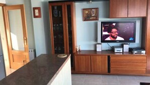 A kitchen with wooden cabinets, a built-in oven, and a television on a wooden stand. - Fake penthouse with sea views and a large terrace (Llançà)
