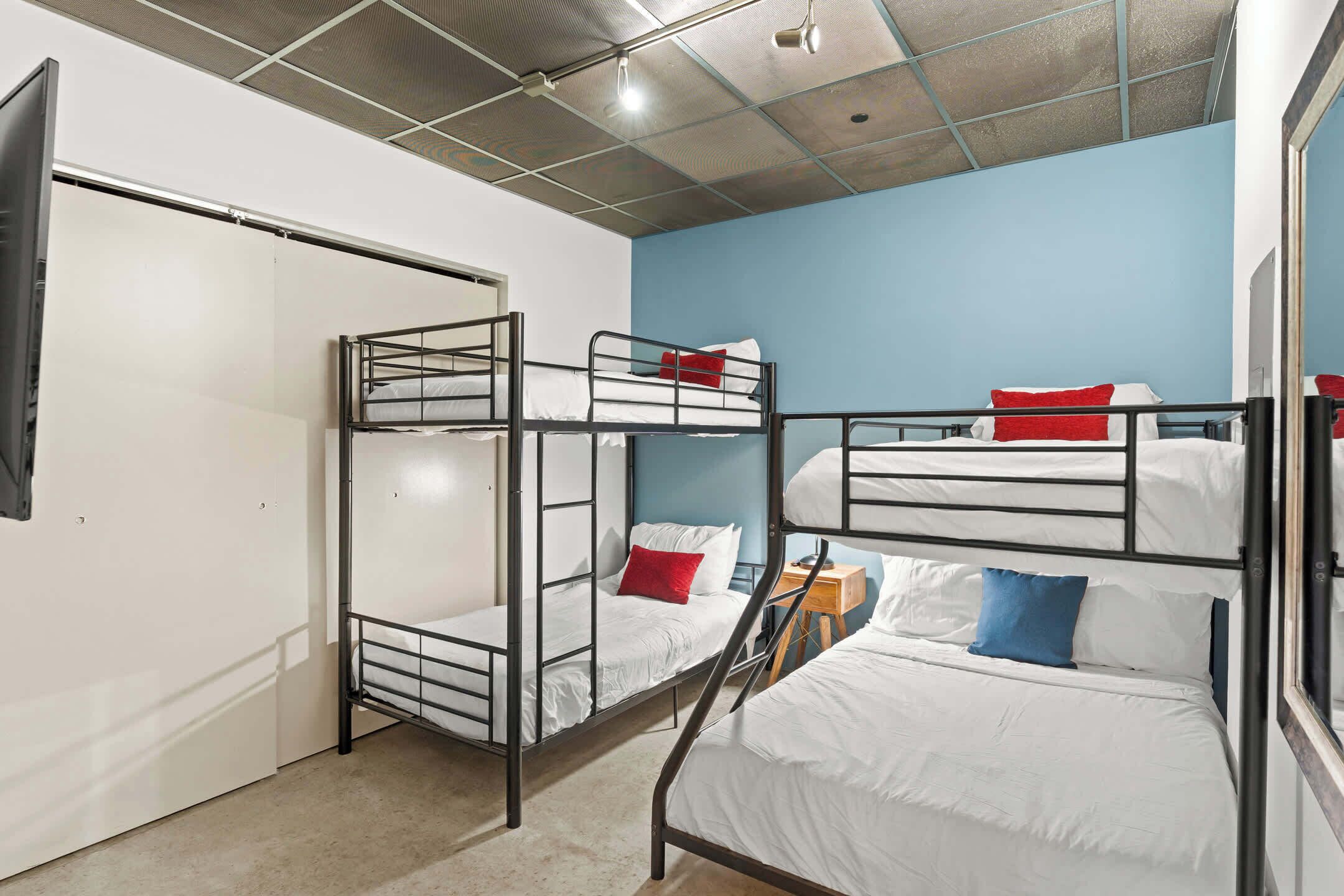 Ein Schlafsaalzimmer mit Etagenbetten, einem Kleiderschrank und einer Decke mit Gittermuster.