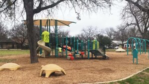 Ein Spielplatz mit Rutsche, Klettergerüsten und einem überdachten Bereich.