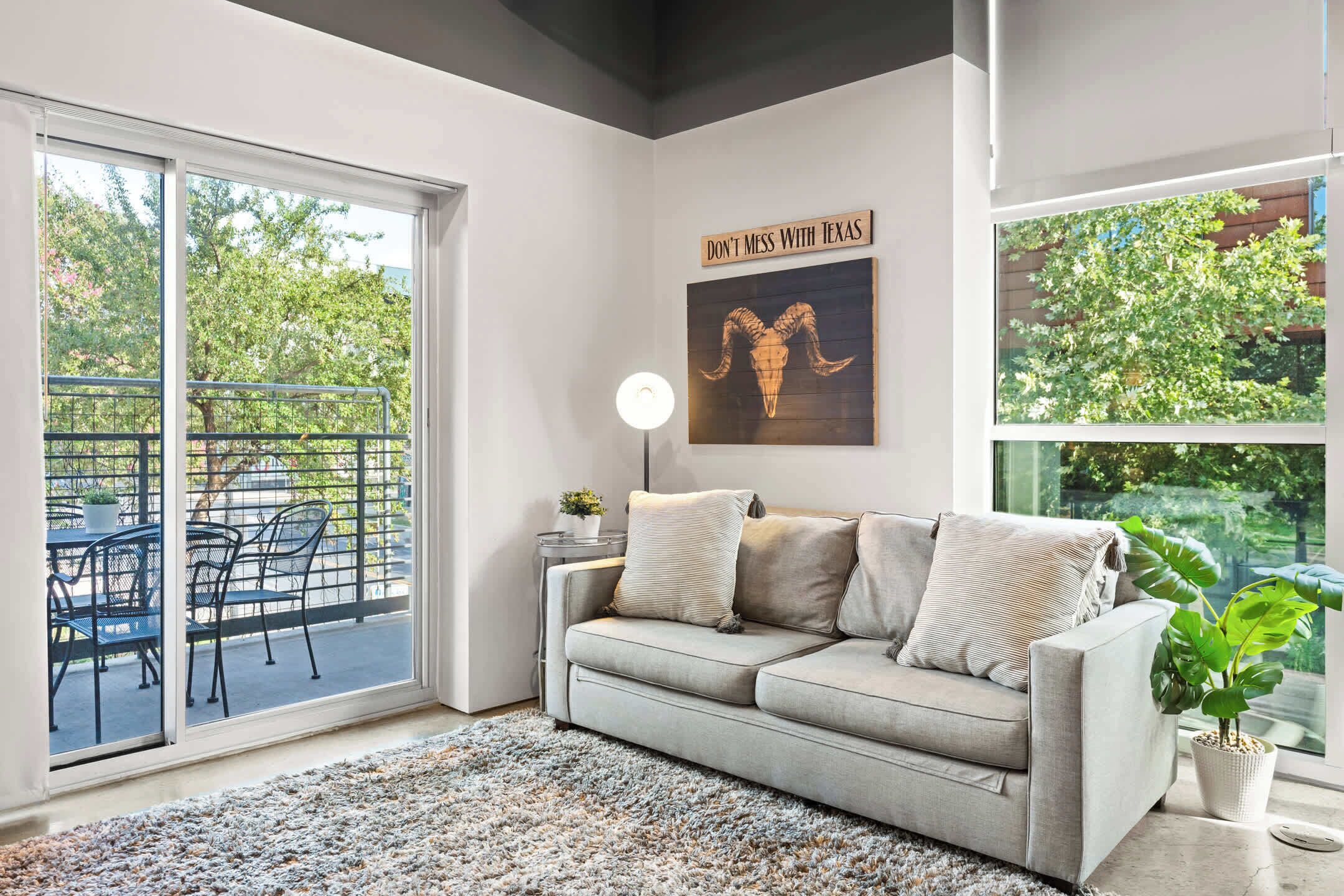 A modern living room with a grey sofa, a black lamp, and a 'DON'T MESS WITH TEXAS' sign.