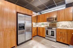 A kitchen with wooden cabinets, stainless steel appliances, a microwave, oven, and a refrigerator.