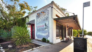 Ein Gebäude mit einem Wandgemälde, das einen Ausstellungsraum und Vintage-Cocktails bewirbt.
