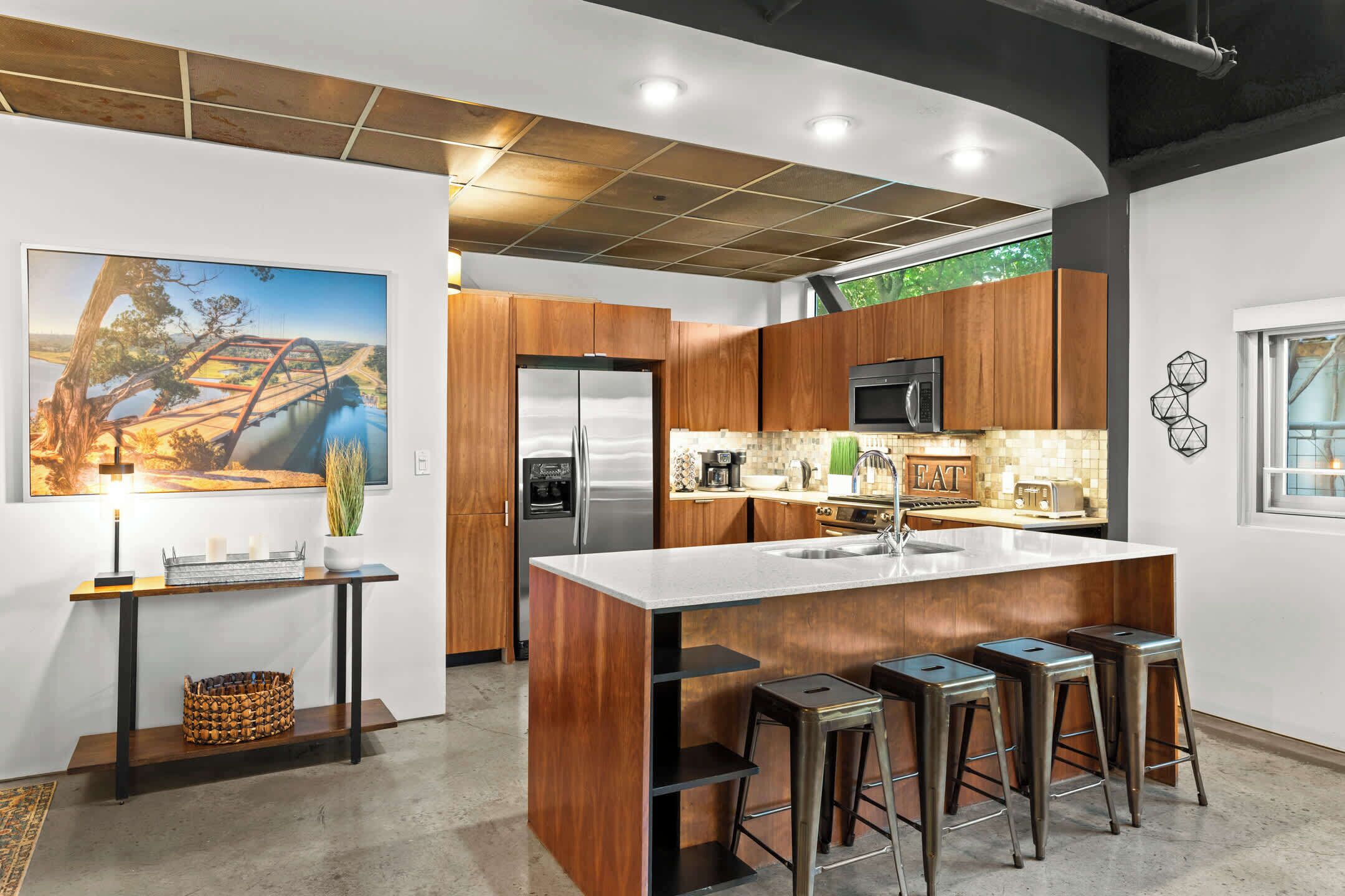 Een moderne keuken met een centraal eiland, roestvrijstalen apparatuur en houten keukenkastjes.