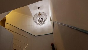 A staircase with a glass railing, a wooden handrail, and a hanging light fixture. - Hotel São Nicolau (Braga)