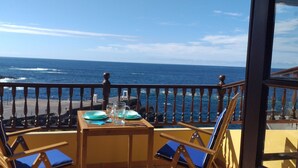 Ein Balkon mit Tisch für zwei Personen mit Blick auf den Ozean.