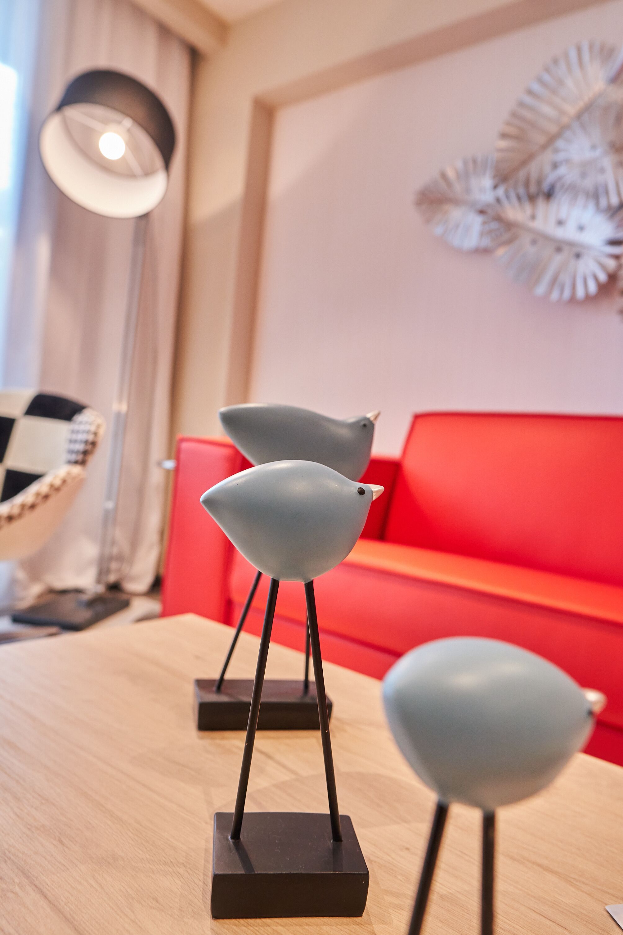 Una sala de estar moderna con una mesa de madera, un sofá rojo y dos esculturas decorativas de aves.