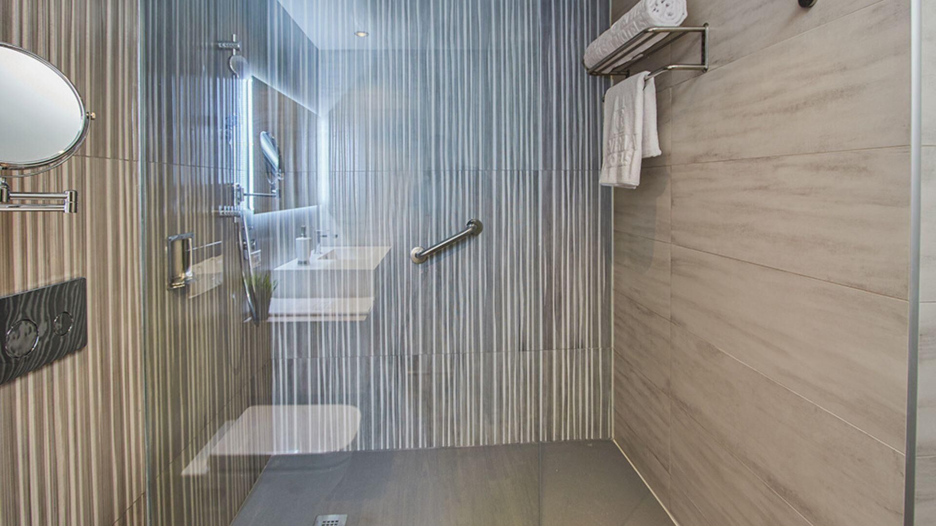 Un baño moderno con cabina de ducha de vidrio, lavabo y perchero para toallas.