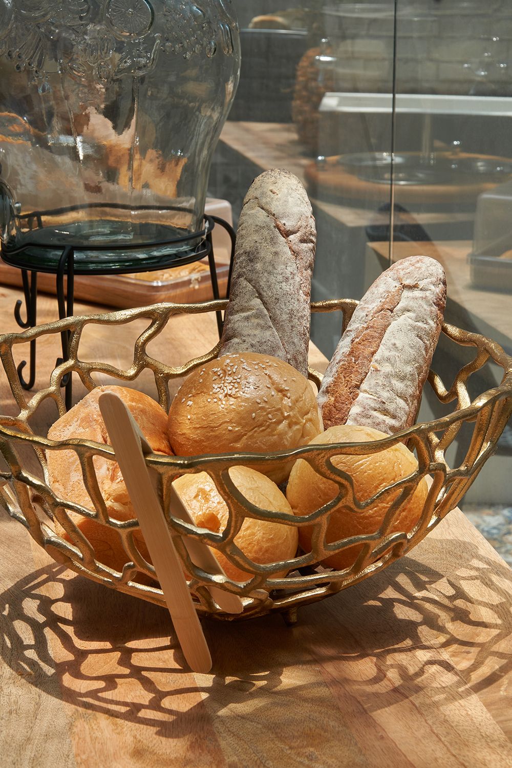 A basket of various breads on a wooden table.