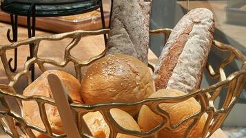 A basket of various breads on a wooden table.