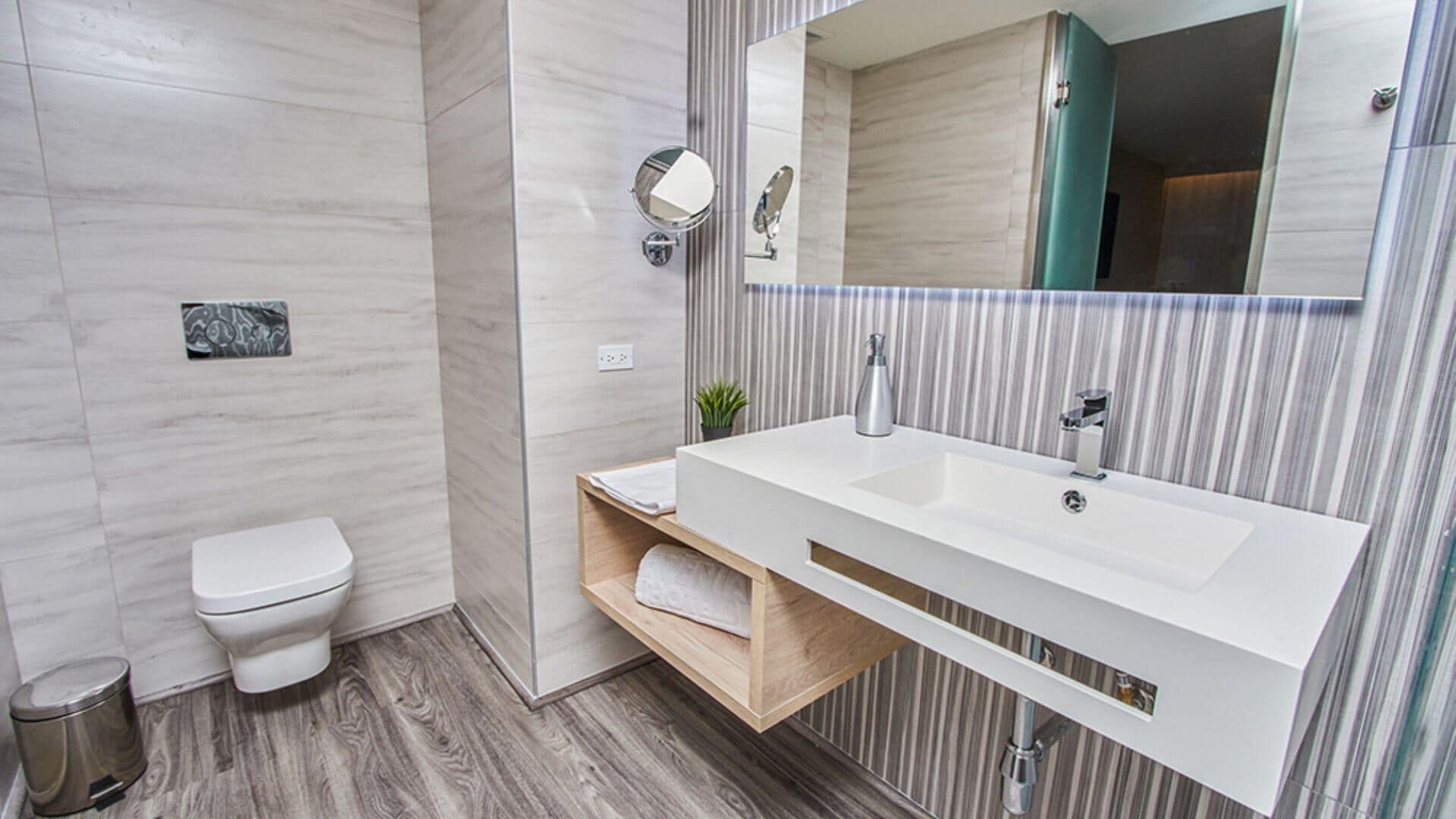 Ein modernes Badezimmer mit Waschbecken, Spiegel und Toilette in Weiß.
