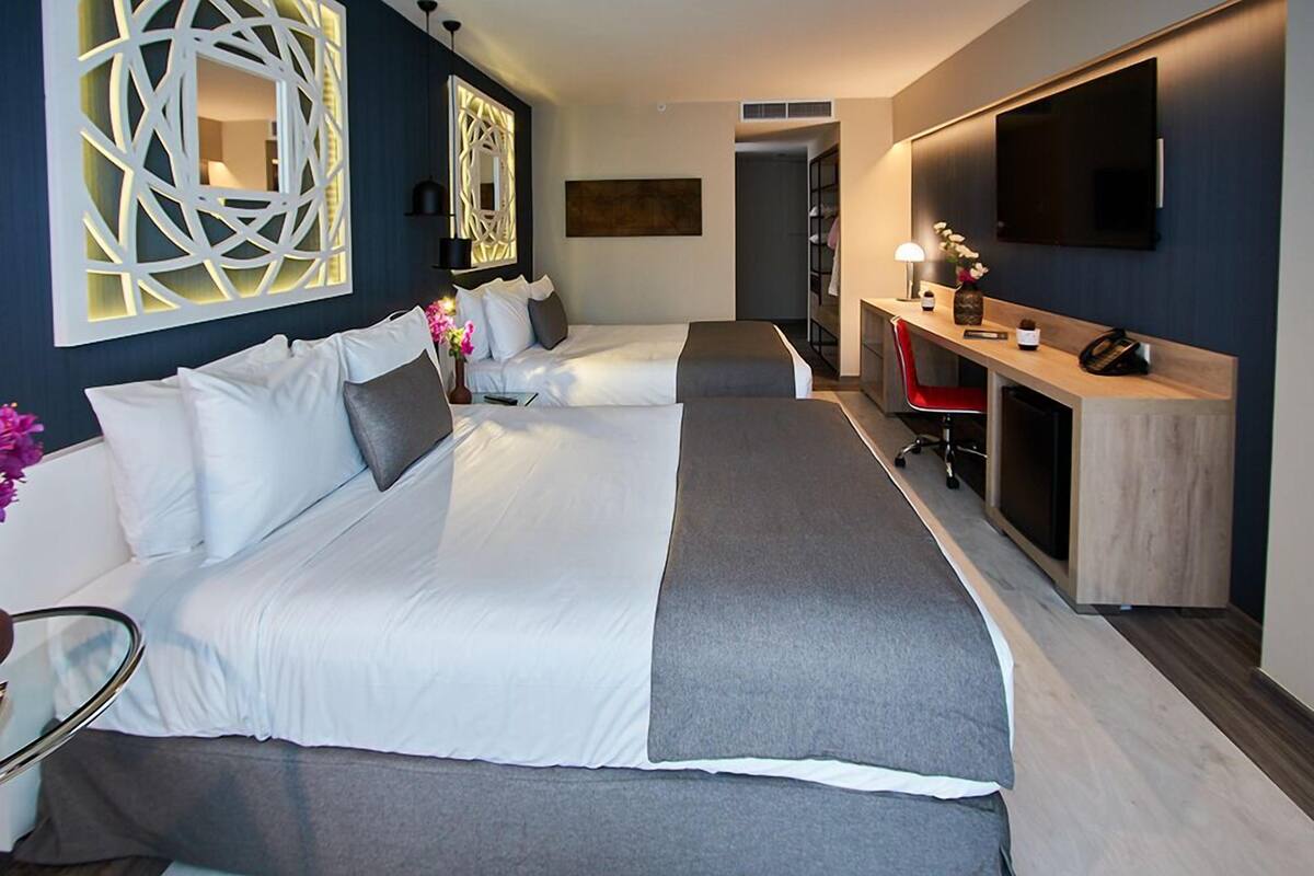 Une chambre d’hôtel moderne équipée de deux lits, d’un bureau, d’une télévision et d’un élément décoratif mural.