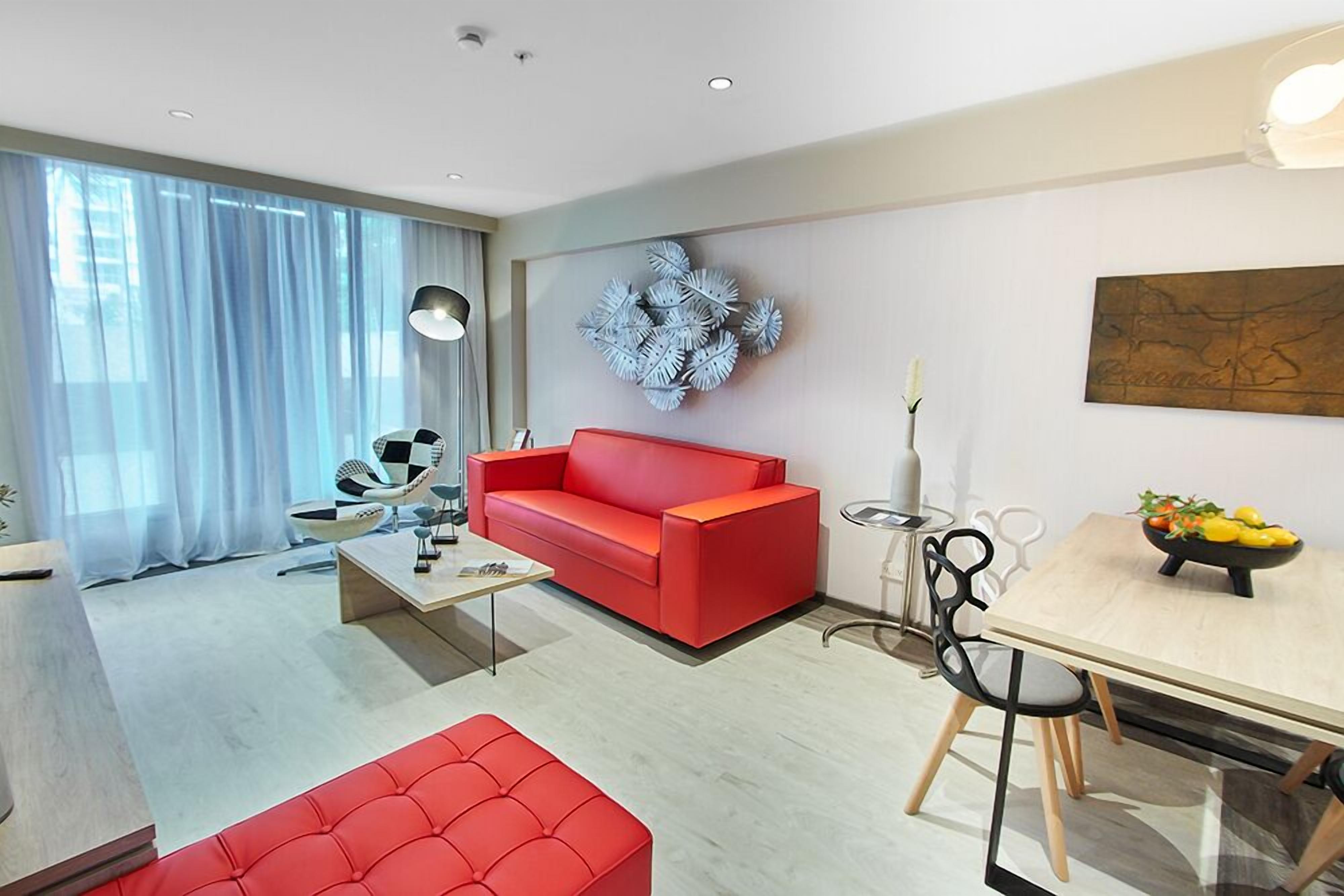 A modern living room with a red sofa, a coffee table, and a dining area with a table and chairs.