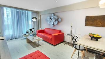 A modern living room with a red sofa, a coffee table, and a dining area with a table and chairs.