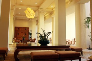 Welcome to our lobby, featuring a large reception desk, comfortable seating, and a lush potted plant.
