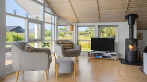 A modern living room with large windows, a flat-screen TV, a fireplace, and comfortable seating. - 3 bedroom lovely home in Jægerspris (Jægerspris)