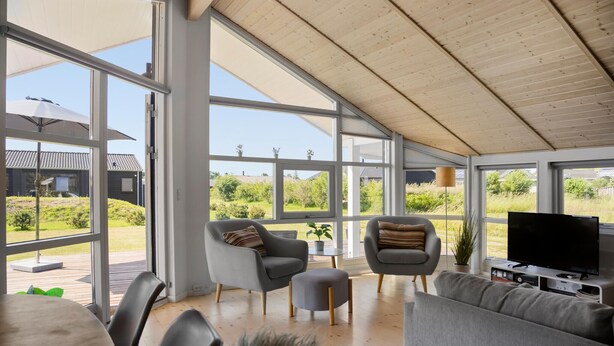A spacious living area with large windows, a wooden ceiling, and modern furniture. - 3 bedroom lovely home in Jægerspris (Jægerspris)
