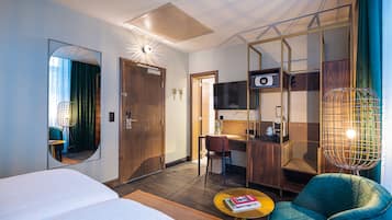 Une chambre d’hôtel équipée d’un lit, d’un bureau, d’une chaise, d’un canapé, d’une machine à café et d’une télévision.