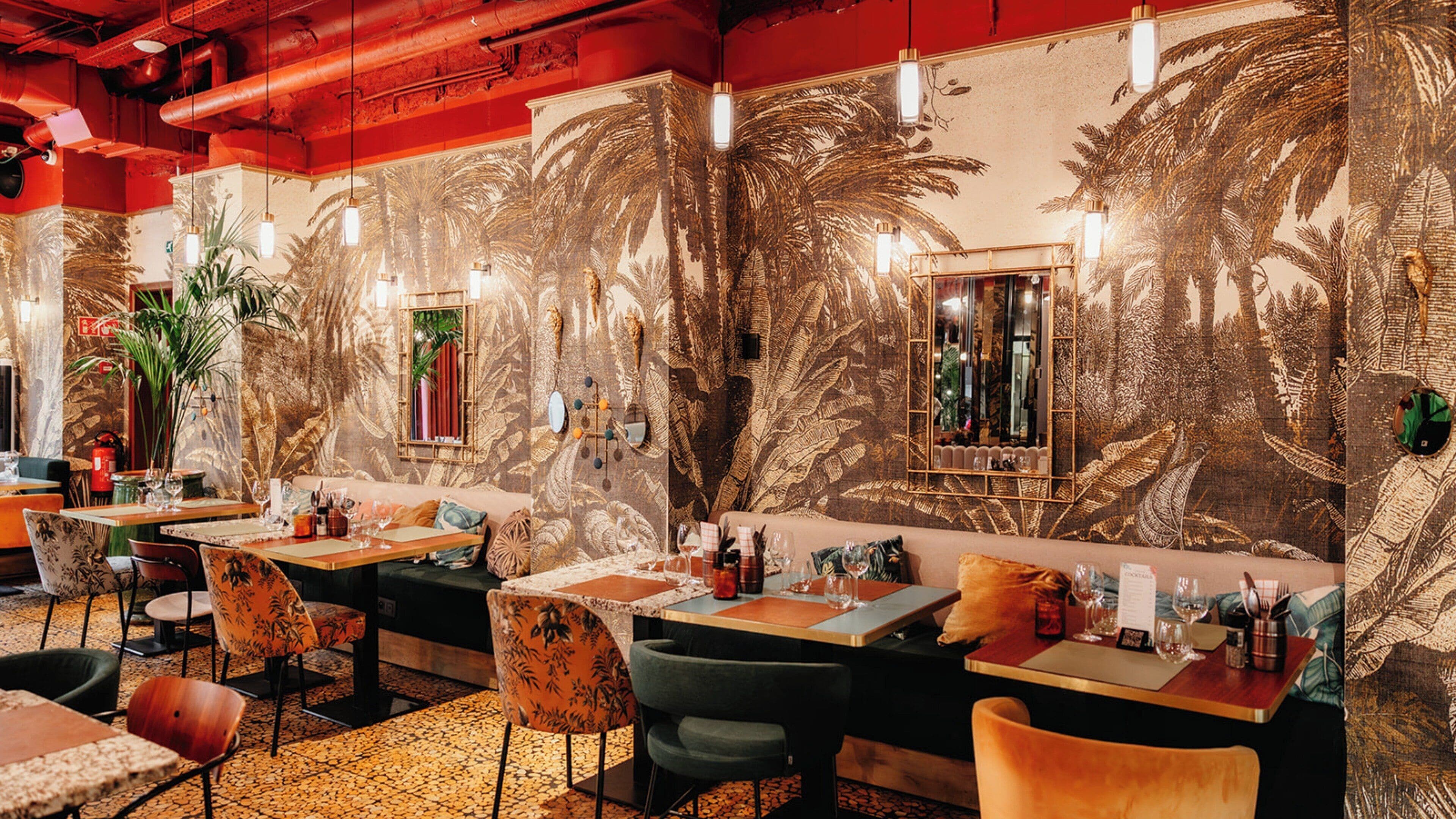 A restaurant with a tropical mural, wooden tables, and cushioned seating.