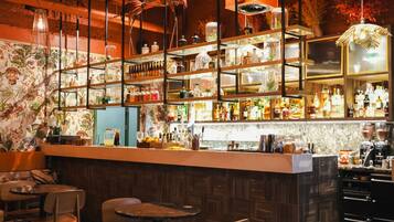 A bar area with shelves of bottles, a counter, and seating.