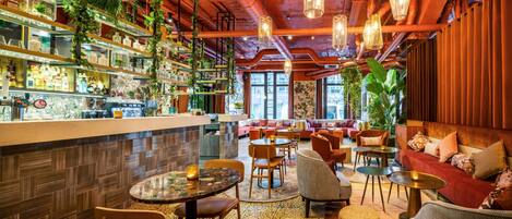 Zona de bar con estantes llenos de botellas y un área de estar con sofás y mesas.