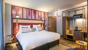 Una habitación de hotel con una cama grande, un armario, un escritorio con cafetera y una mesita de noche.