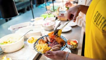 A buffet with various dishes including scrambled eggs, sausages, and a variety of side dishes.
