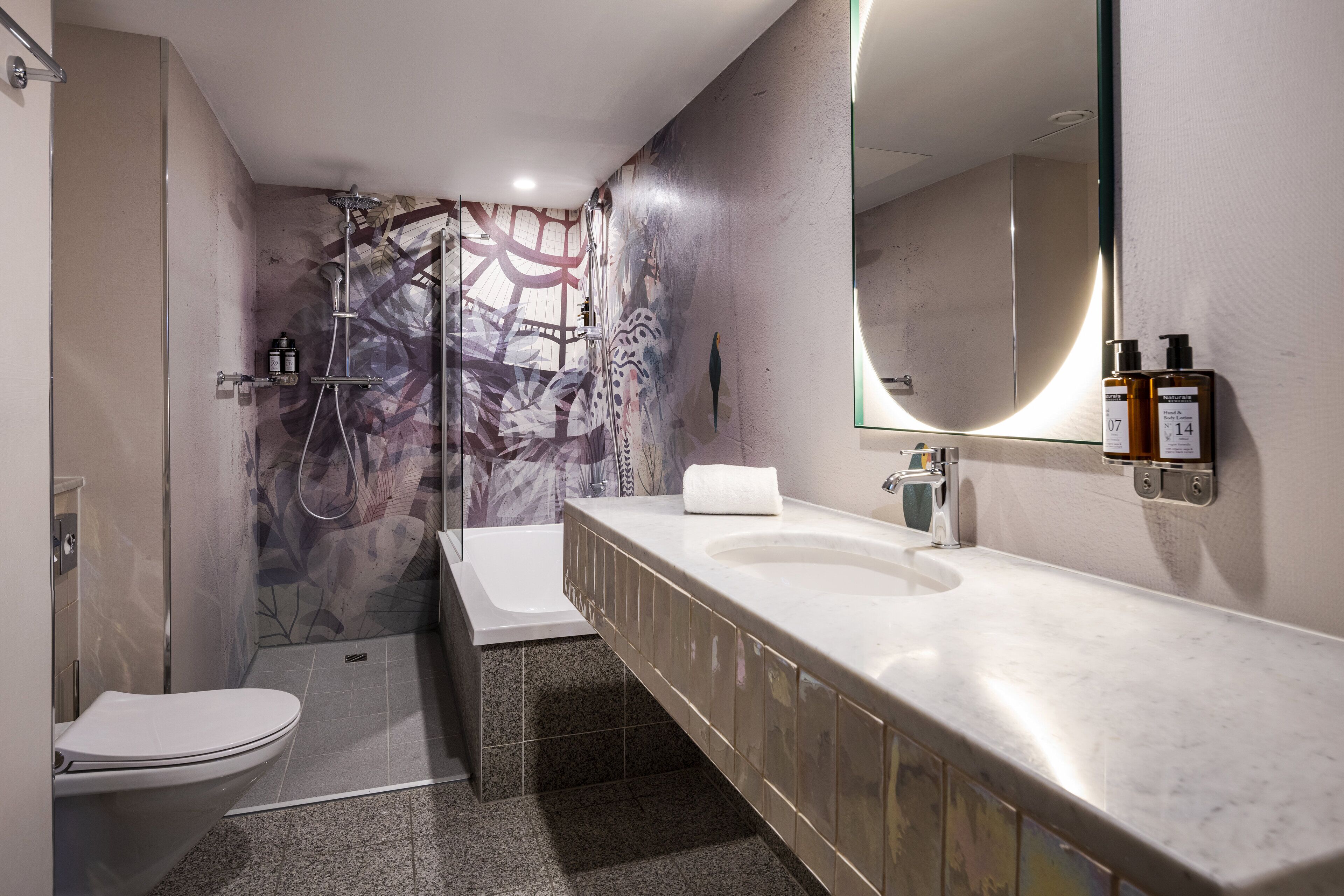 A modern bathroom with a shower, toilet, and vanity.