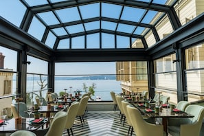 Un restaurante con techo de vidrio, mesas dispuestas para comer y vista al agua.