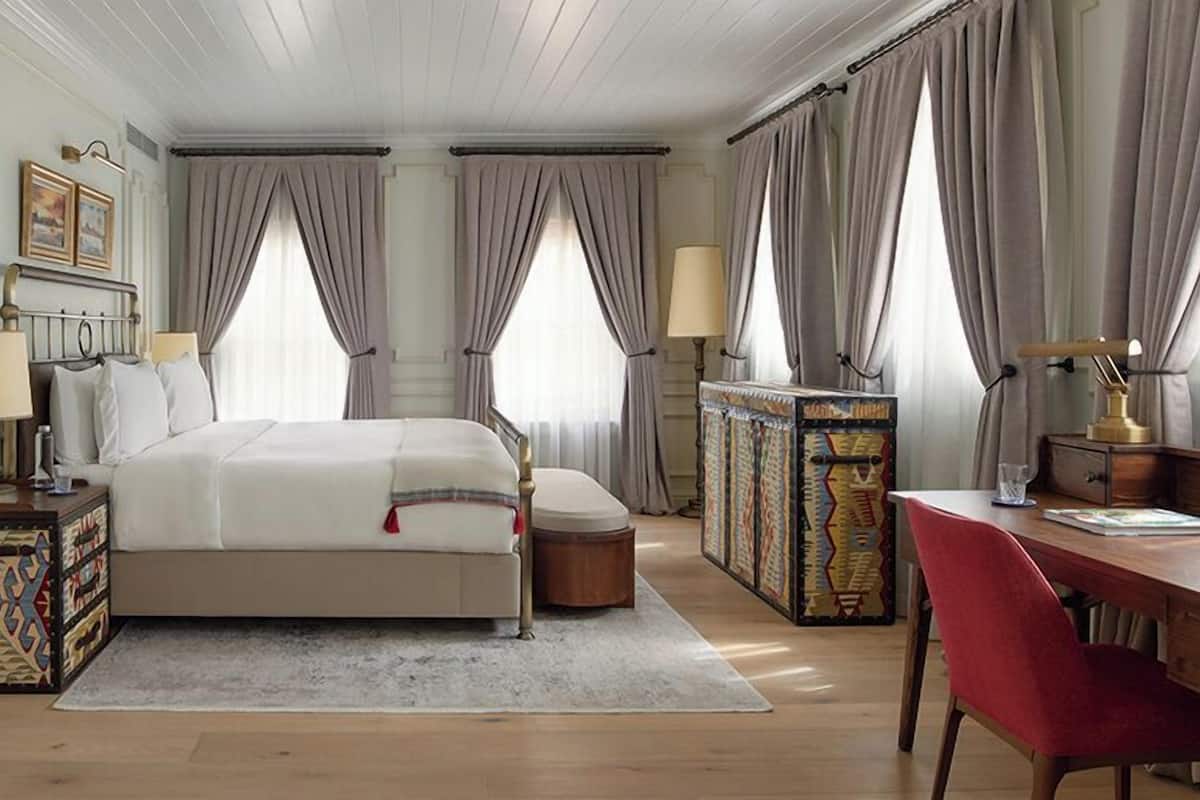 A bedroom with a bed, bedside tables, a desk, and a chair.