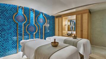 Two beds with crisp linens, a large mirror, and a decorative mosaic wall.