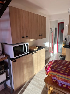 Une cuisine compacte dotée de meubles en bois, d’un four à micro-ondes et d’un petit coin repas avec une table et des chaises.