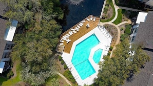 Vista aérea de una propiedad con piscina, terraza con sillas de descanso y vegetación circundante.