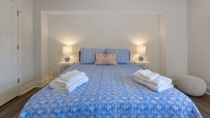 Un dormitorio con una cama grande, dos lámparas de noche, una almohada y toallas dobladas.