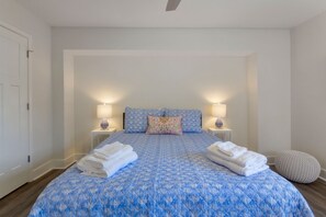 A bedroom with a large bed, two bedside lamps, a pillow, and folded towels. - HIDEAWAY VILLA: Walk to Beach & Coligny,Pool, Fireplace, 3BR/3.5 BA (Hilton Head Island)