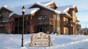 A large, multi-story building with a snow-covered roof and a sign indicating it is part of Mountain Resorts. - Quail Run - 3367 (Steamboat Springs)