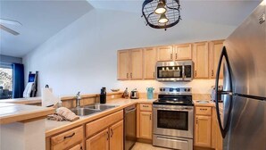 A modern kitchen with wooden cabinets, stainless steel appliances, and a built-in oven. - Quail Run - 3367 (Steamboat Springs)