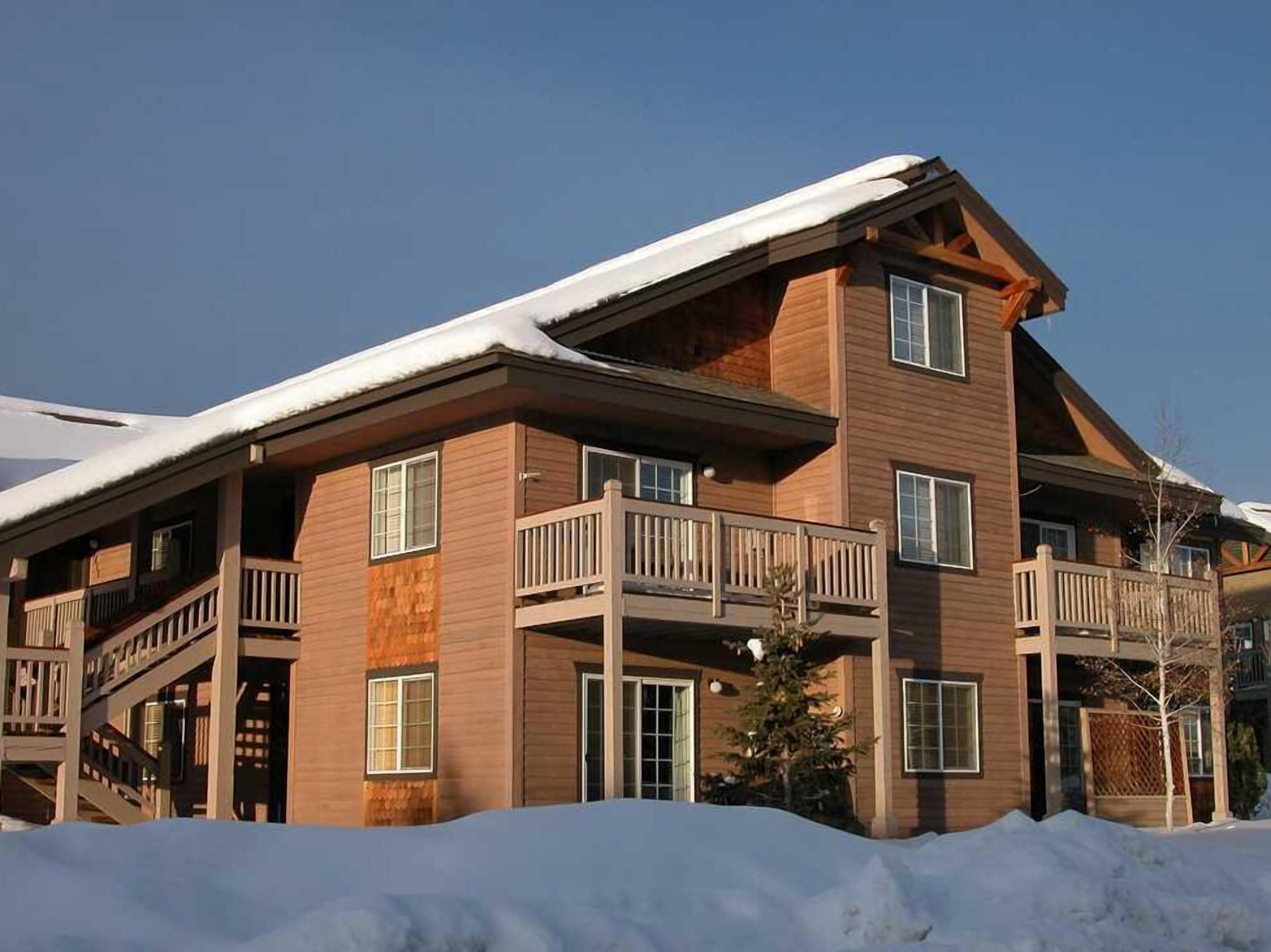 A multi-story lodge with wooden exterior and balconies, surrounded by snow.